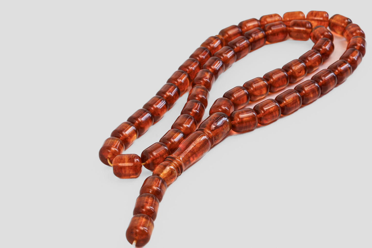 Detailed view of the كهرمان شفاف (transparent amber) rosary, with clear, faceted beads on a white background.
