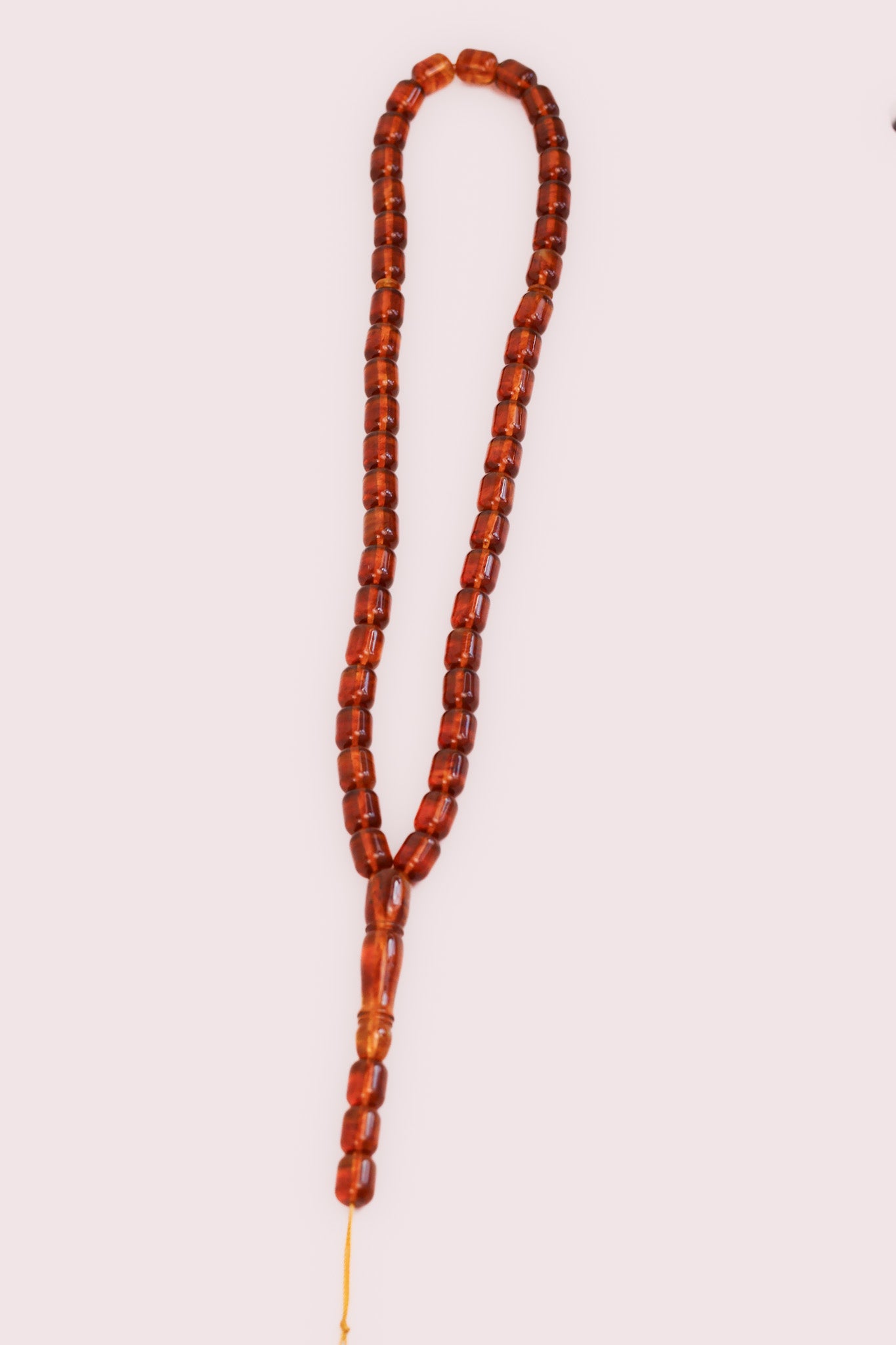 Full view of the 30 g amber prayer beads (Bernstein Gebetskette), transparent brown on a light background.