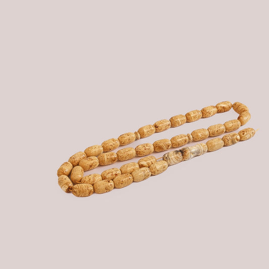 Full view of the 65 g amber prayer beads (Bernstein Gebetskette), wood grain pattern, on a light background.