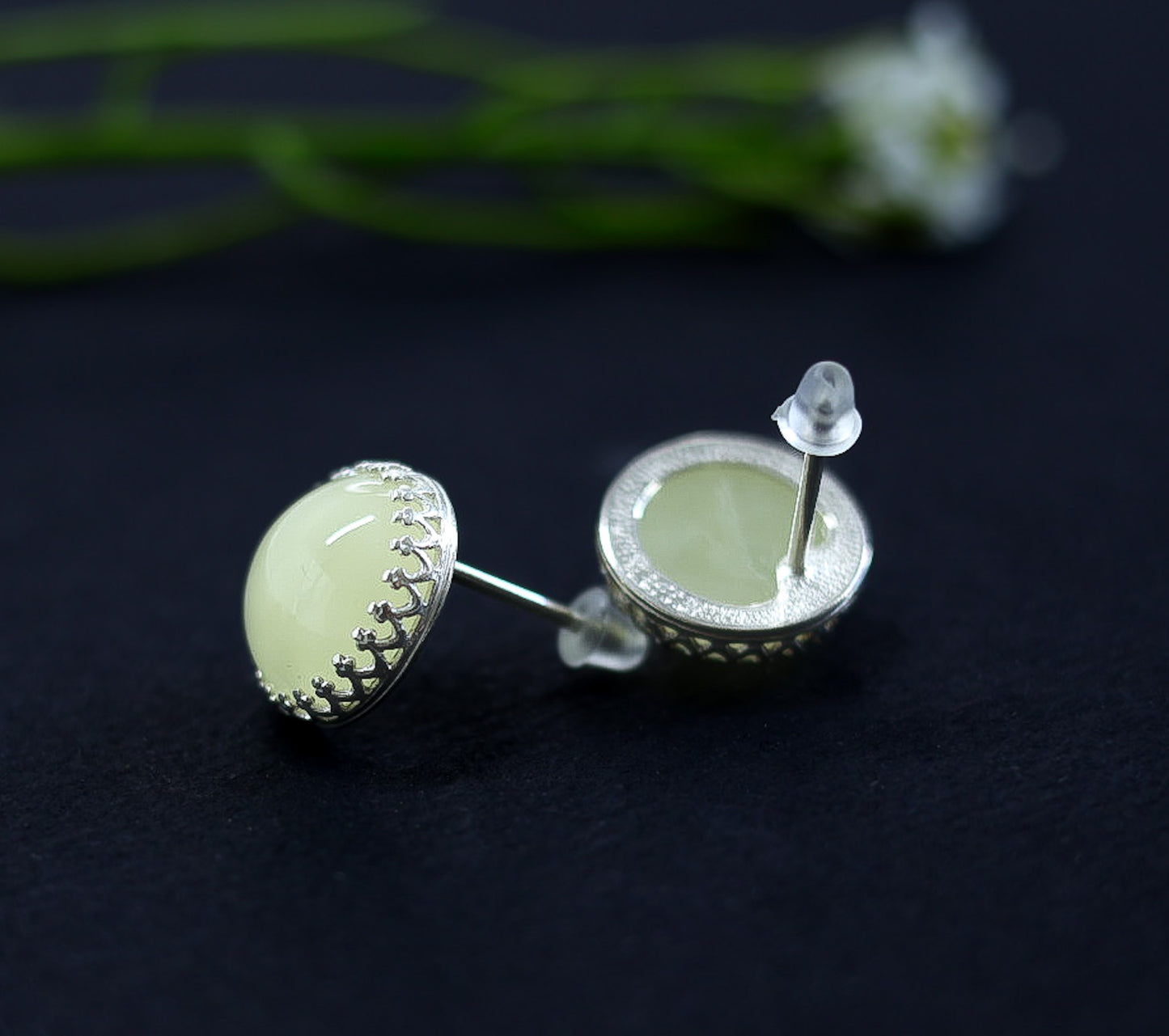 Pair of green amber earrings with crown silver frame on a dark background