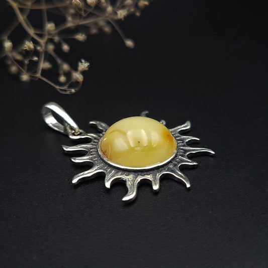 Nahaufnahme des runden, milchigen Baltischen Bernsteins im silbernen Sonnenrahmen.