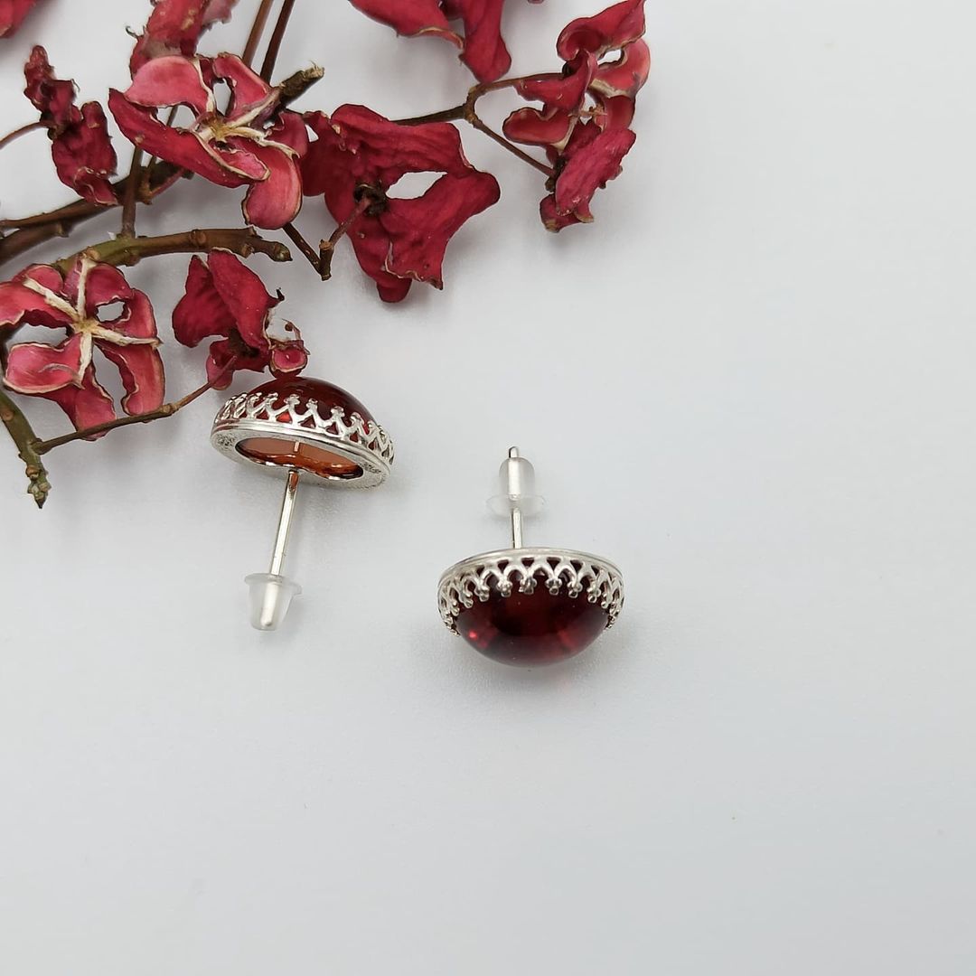 Handgefertigte Bernstein Ohrstecker von Tetibel Jewels auf schwarzem Hintergrund. Die Stecker bestehen aus ⌀12mm Cognac Bernstein und 925 Sterling Silber.