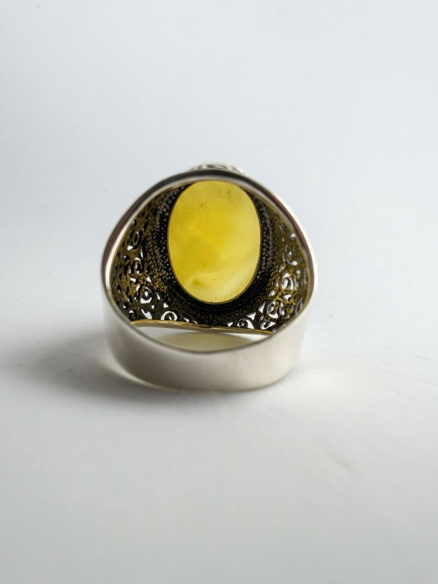 Natural yellow Baltic amber dome stone set in an intricate filigree-engraved sterling silver band.