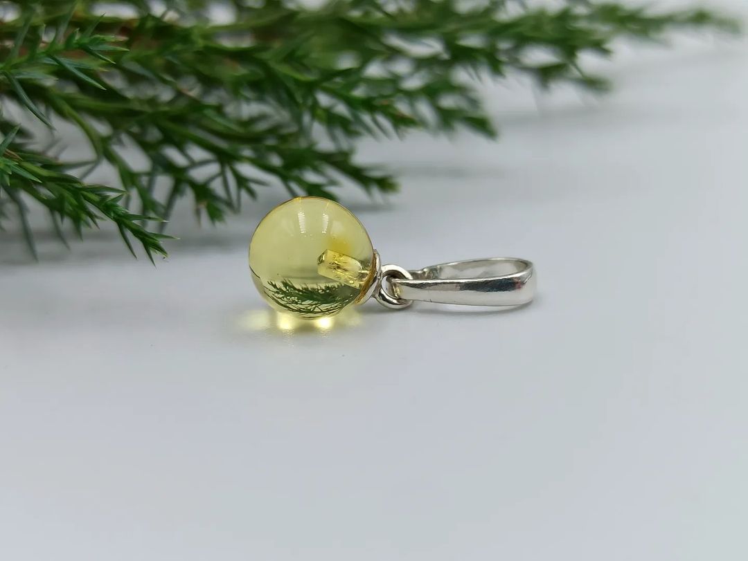 Close-up of genuine Baltic amber ball pendant in silver setting