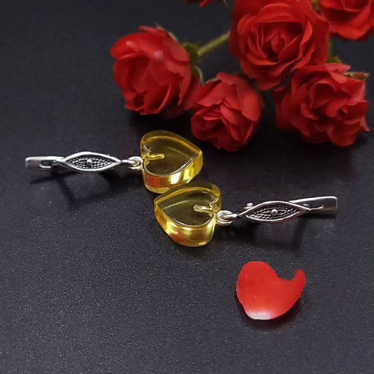 Back view of two oval Tetibel milky yellow amber stud earrings in 925 Sterling Silver, clearly showing the leverback clasp and the twisted rope bezel setting. The light, milky amber is clearly visible.