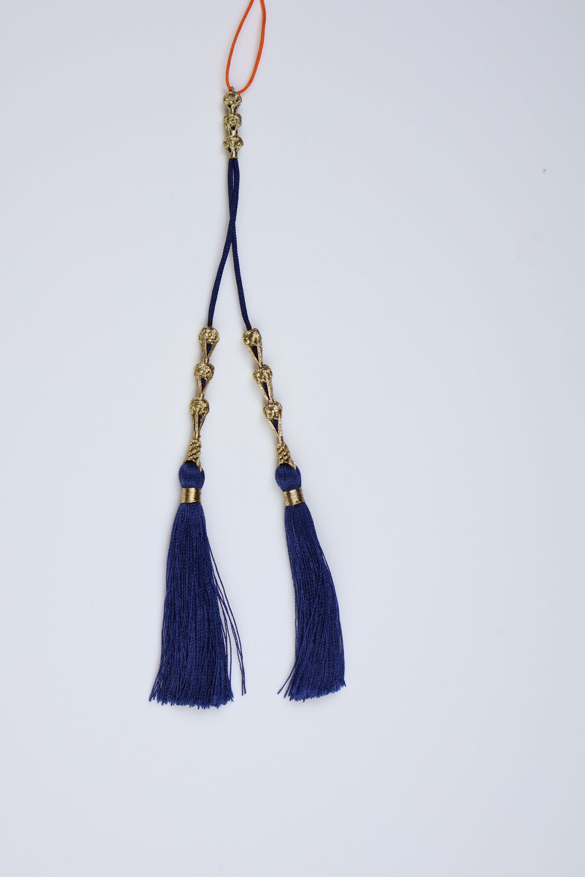 A pair of traditional Chinese silk tassels, likely for a hairpin or as a decorative accessory, featuring deep navy blue tassels, gold metal links, and a small orange cord loop at the bottom, set against a plain light gray background.