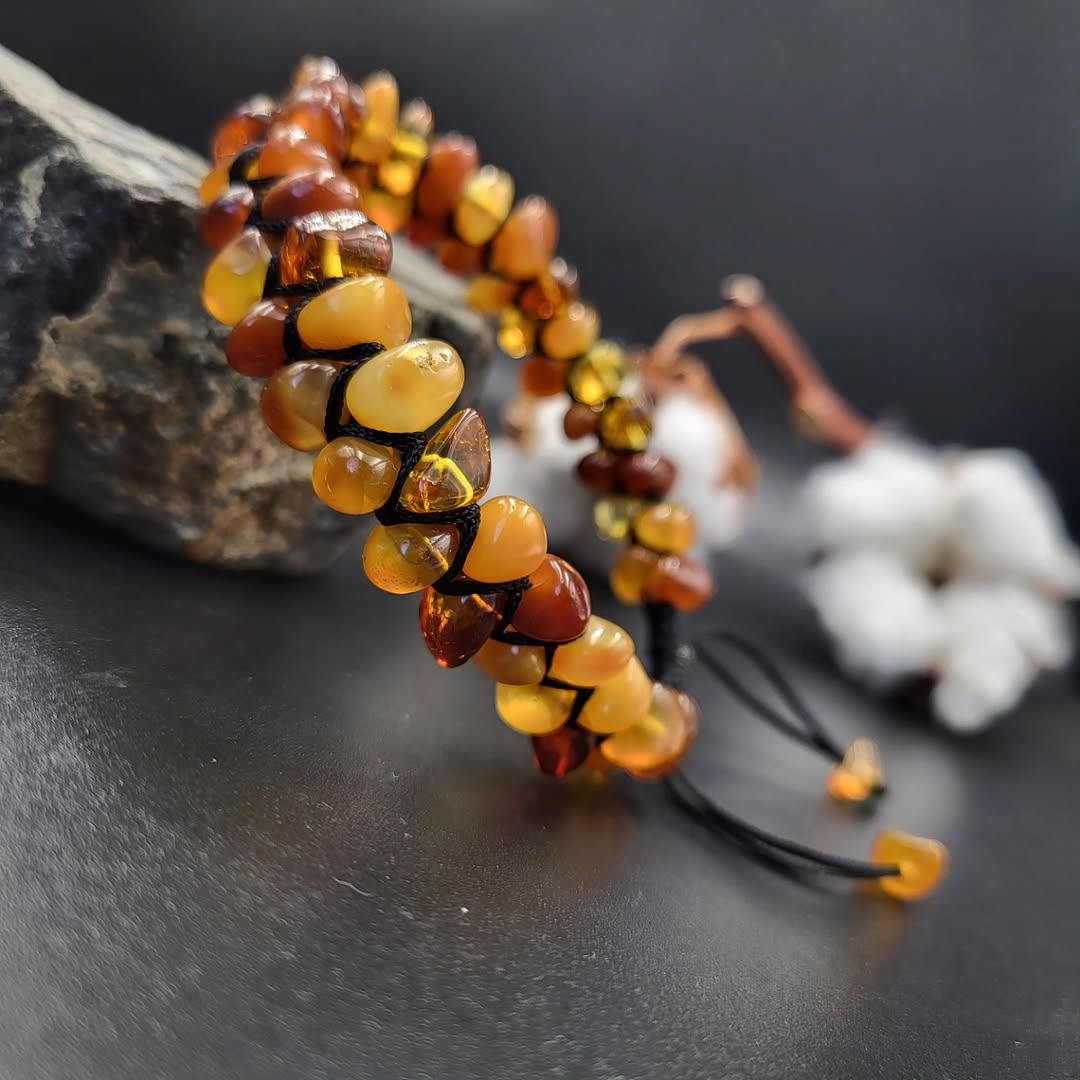 Angled view of a Tetibel Macramé Amber Bracelet featuring natural, rough Baltic amber stones in varying shades of brown and yellow