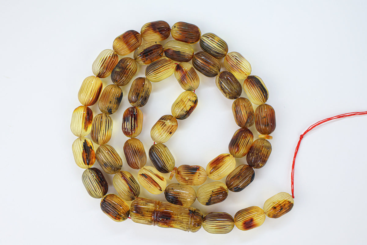 Handcrafted brown succinite amber tasbih featuring 42 authentic 16.5x10.5mm carved beads with minor natural imperfections and a handmade blue and white tassel from Doha, Qatar.