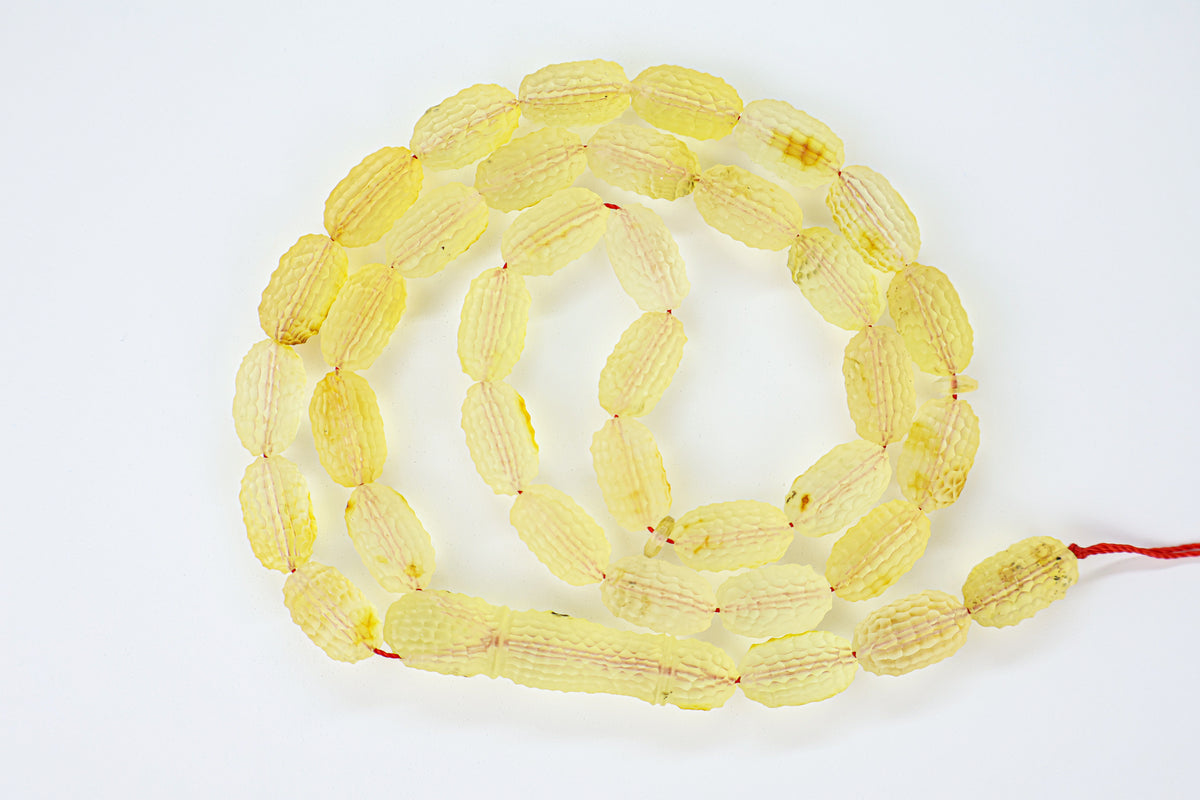 Authentic grooved hand-carved translucent yellow Baltic amber misbaha strand displaying natural minor character marks and a matching carved amber imam.