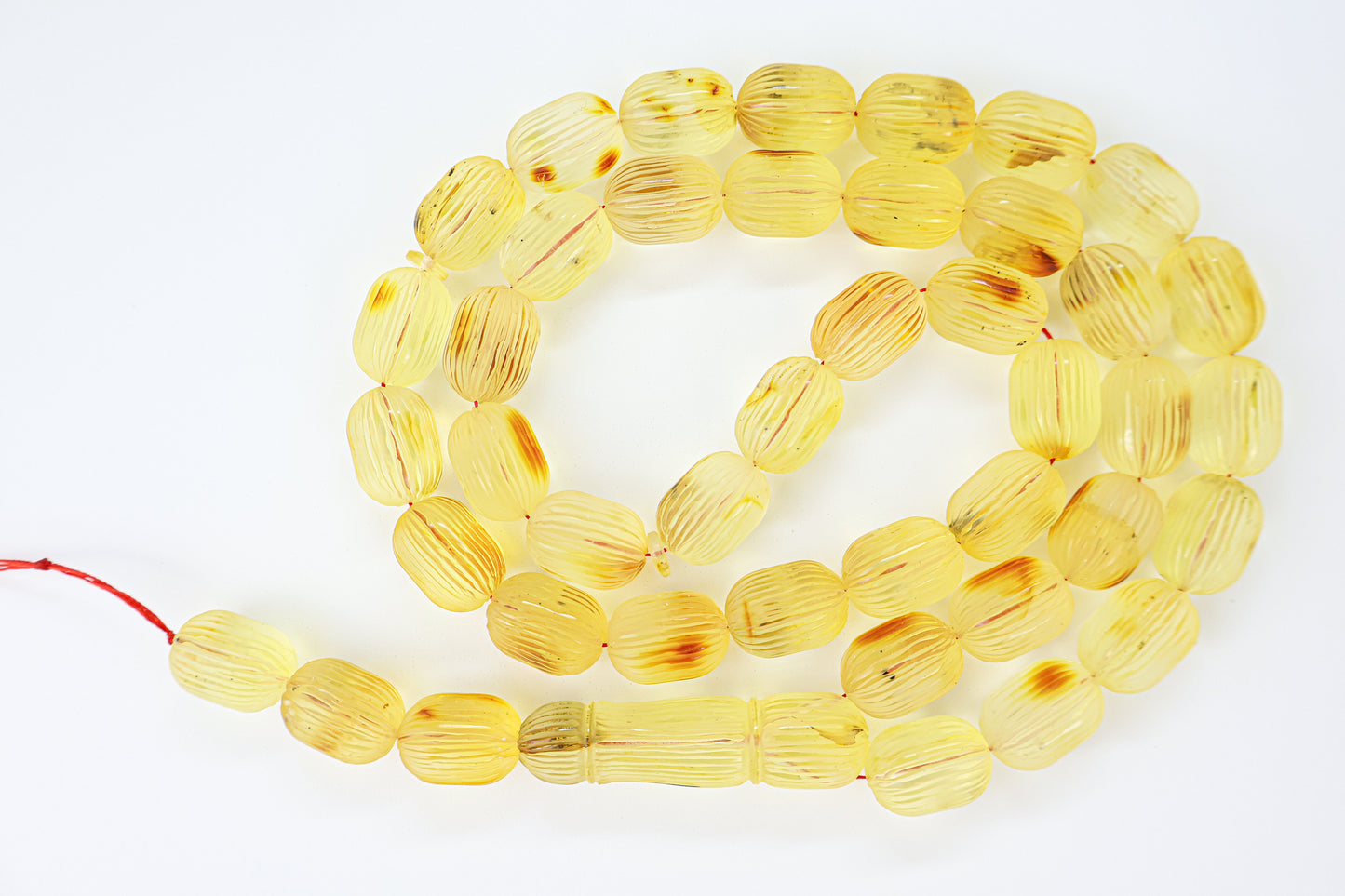 Authentic grooved hand-carved Baltic amber misbaha strand displaying natural minor imperfections and a matching carved amber imam.