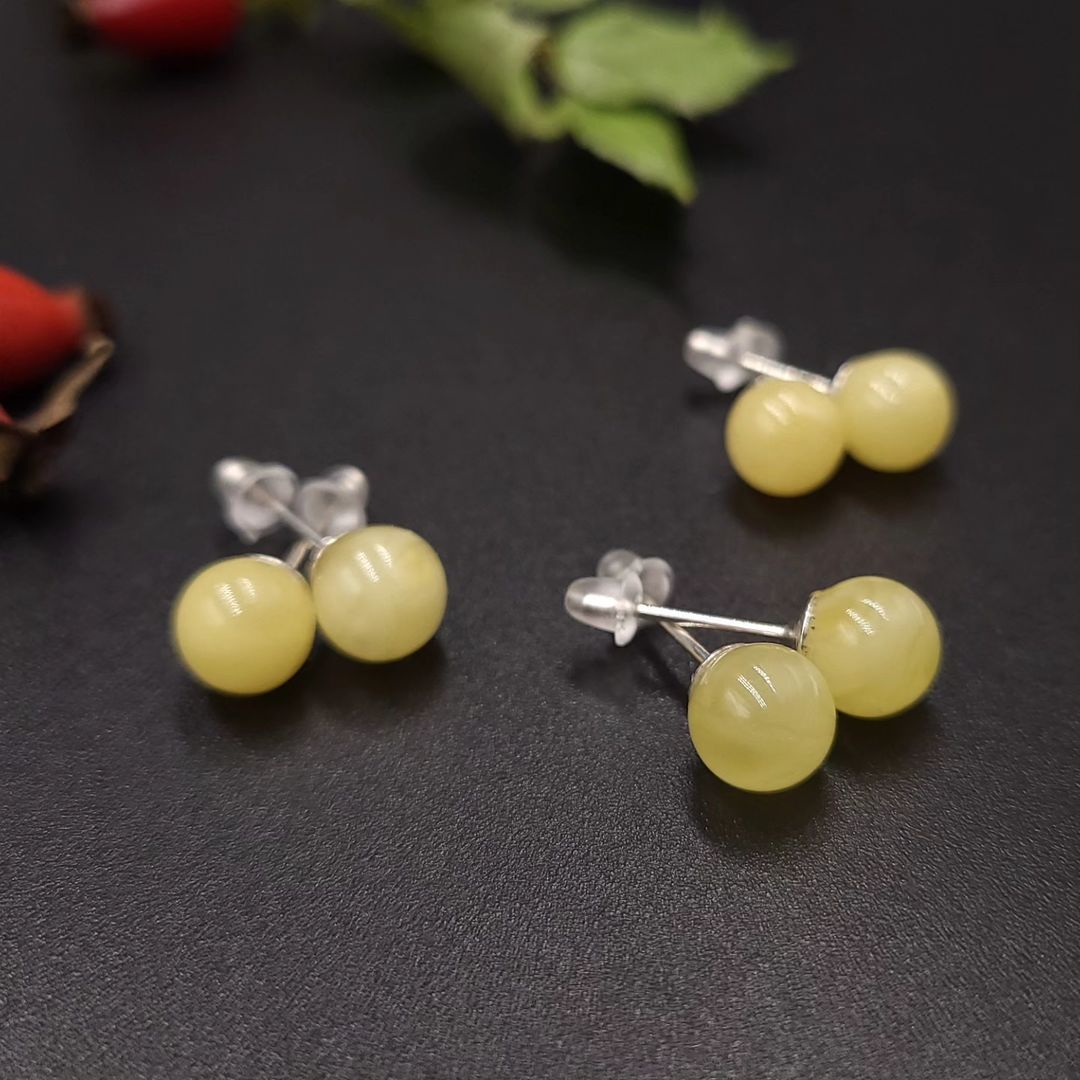 Sortiment der Lemon Bernstein Ohrringe (7mm, 8mm, 9mm), präsentiert auf einem Hagebutten-Zweig.