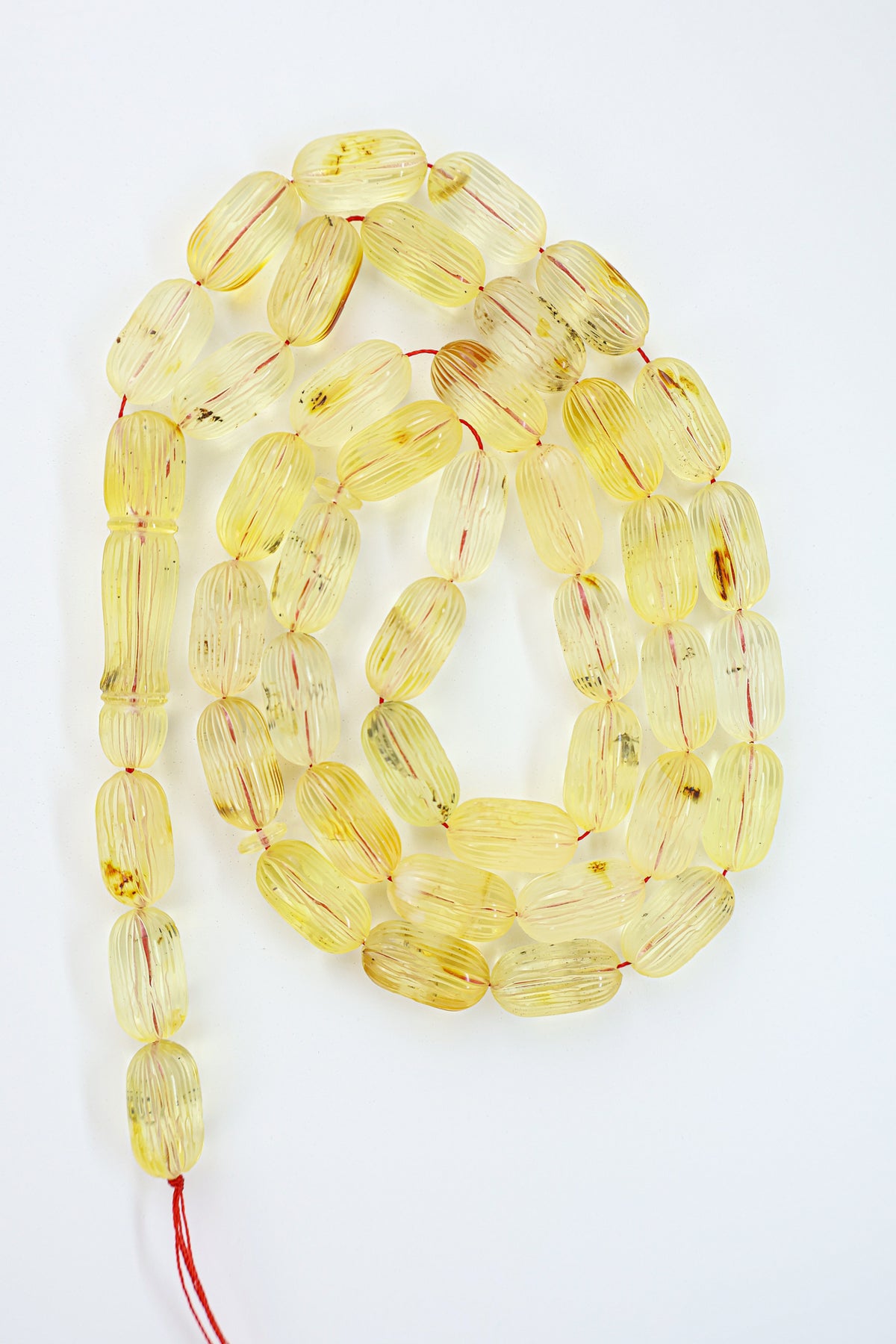 Authentic grooved hand-carved yellow-brown Baltic amber misbaha strand displaying natural minor imperfections and a matching carved amber imam.