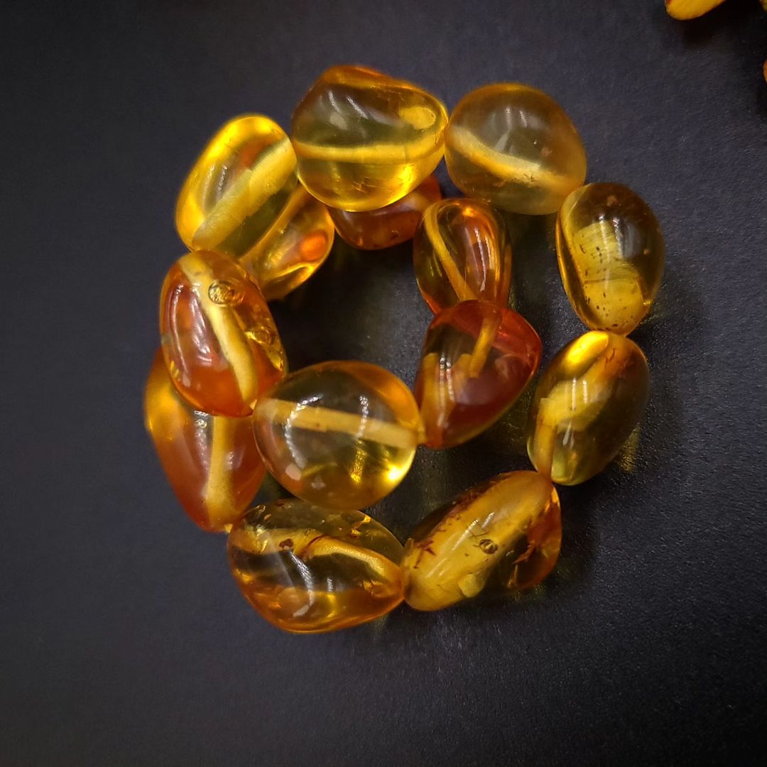 Honig Bernstein Armband, präsentiert mit gelben Blumen auf dunklem Hintergrund.