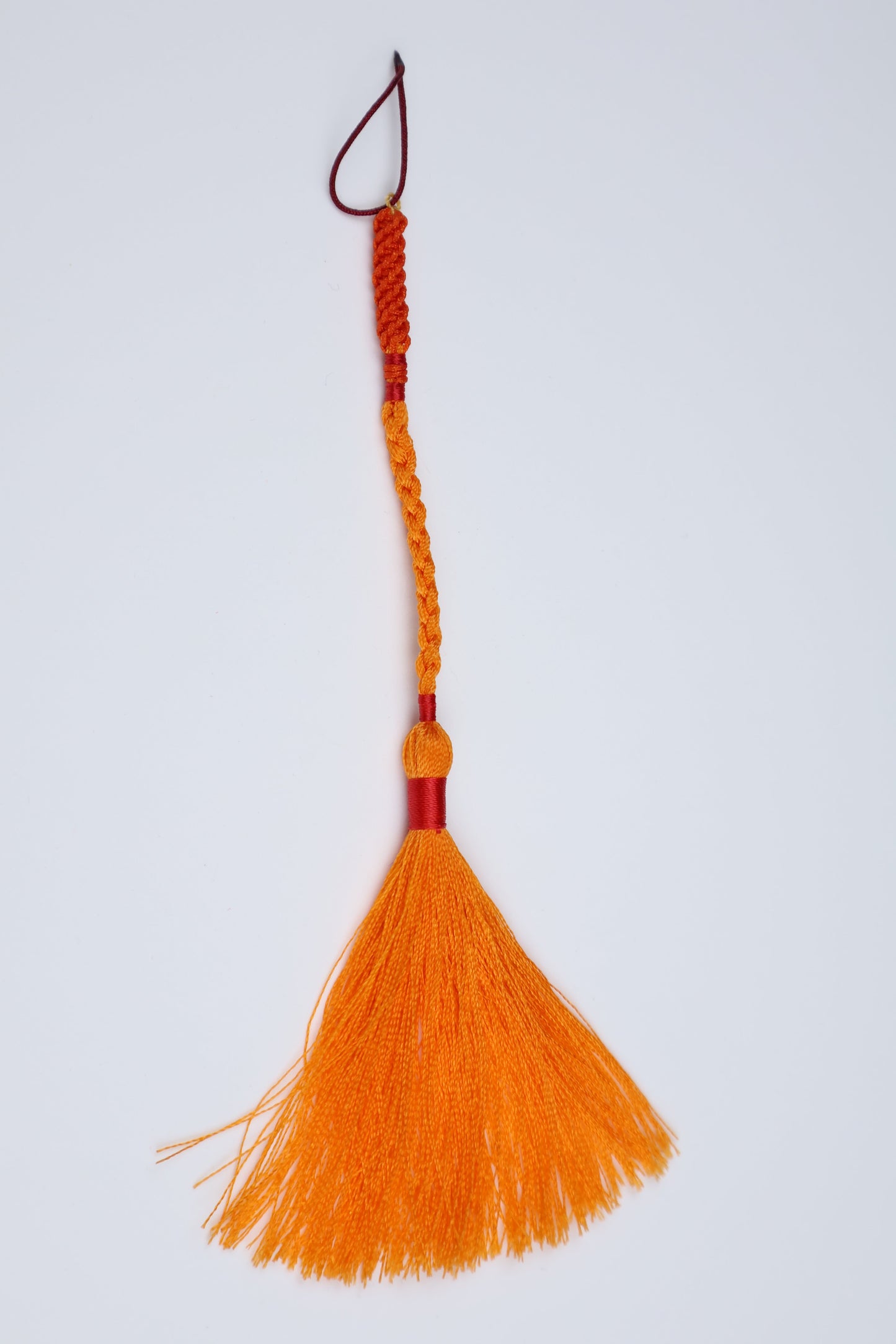 An orange decorative tassel with a braided cord handle and a small hanging loop, ideal for amber mesbah.