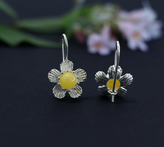Milchgelbe Bernstein Ohrringe im Blumen-Design. Nahaufnahme der ⌀16mm Silberblüte und des zentralen Bernsteinkabochons.