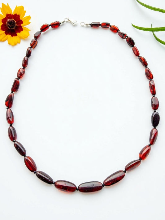 Handcrafted 50cm natural Baltic amber necklace with polished elongated cherry red olive beads and a sterling silver clasp by Tetibel.