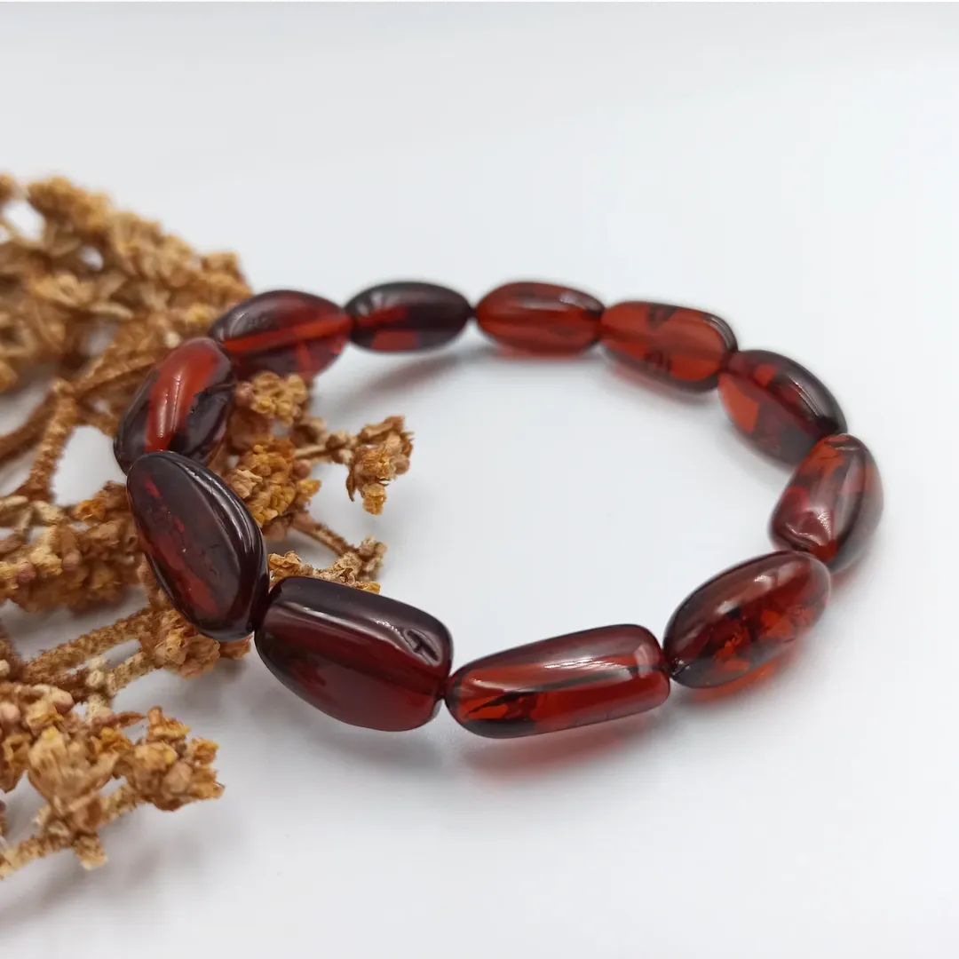 Elegantes Bernsteinarmband mit glänzend polierten Olivenperlen auf weißem Hintergrund.