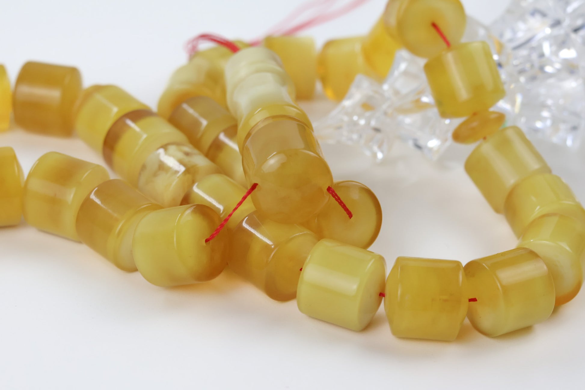 Close-up of butterscotch pressed Baltic amber barrel beads showing natural marbling and polish finish