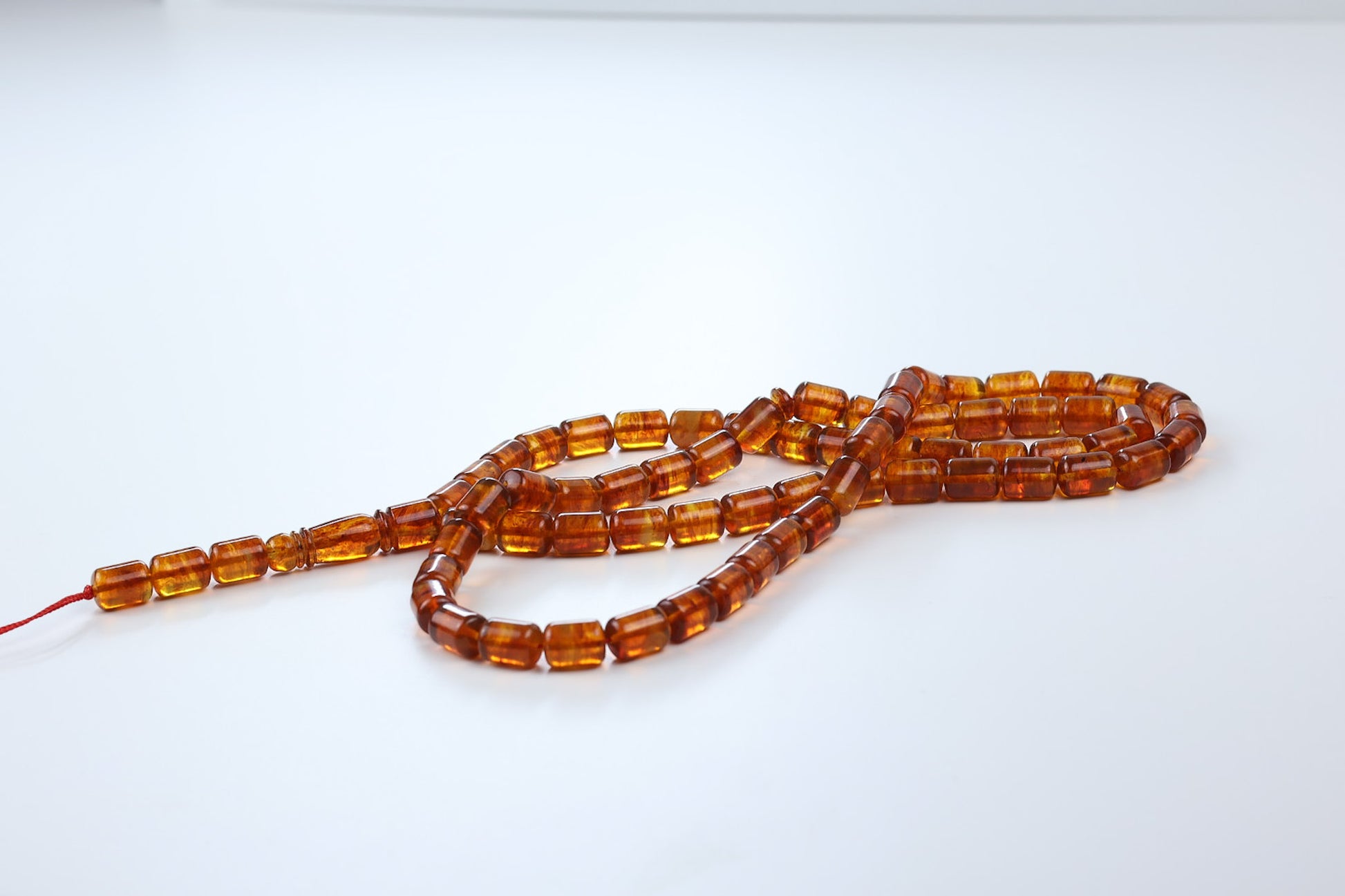 Macro detail of pressed cognac Baltic amber rosary beads showing natural inclusions and warm golden glow