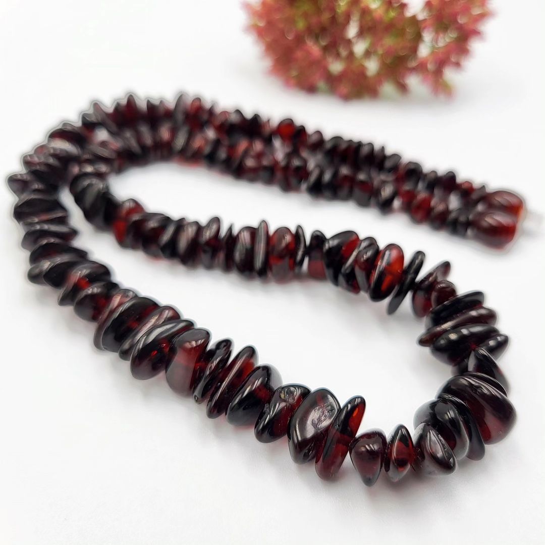Bernstein-Splitterkette (Kirschrot) von Tetibel spiralförmig gelegt. Zeigt die tiefrote Farbe und den Kunststoffverschluss.