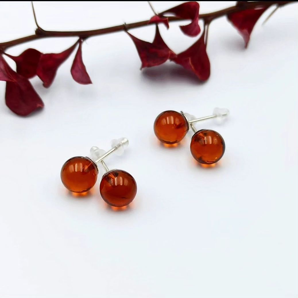 Drei Paare Cognac Baltische Bernstein Kugel-Ohrstecker (⌀7mm, ⌀8mm, ⌀9mm) mit Silberstiften auf weißem Hintergrund.