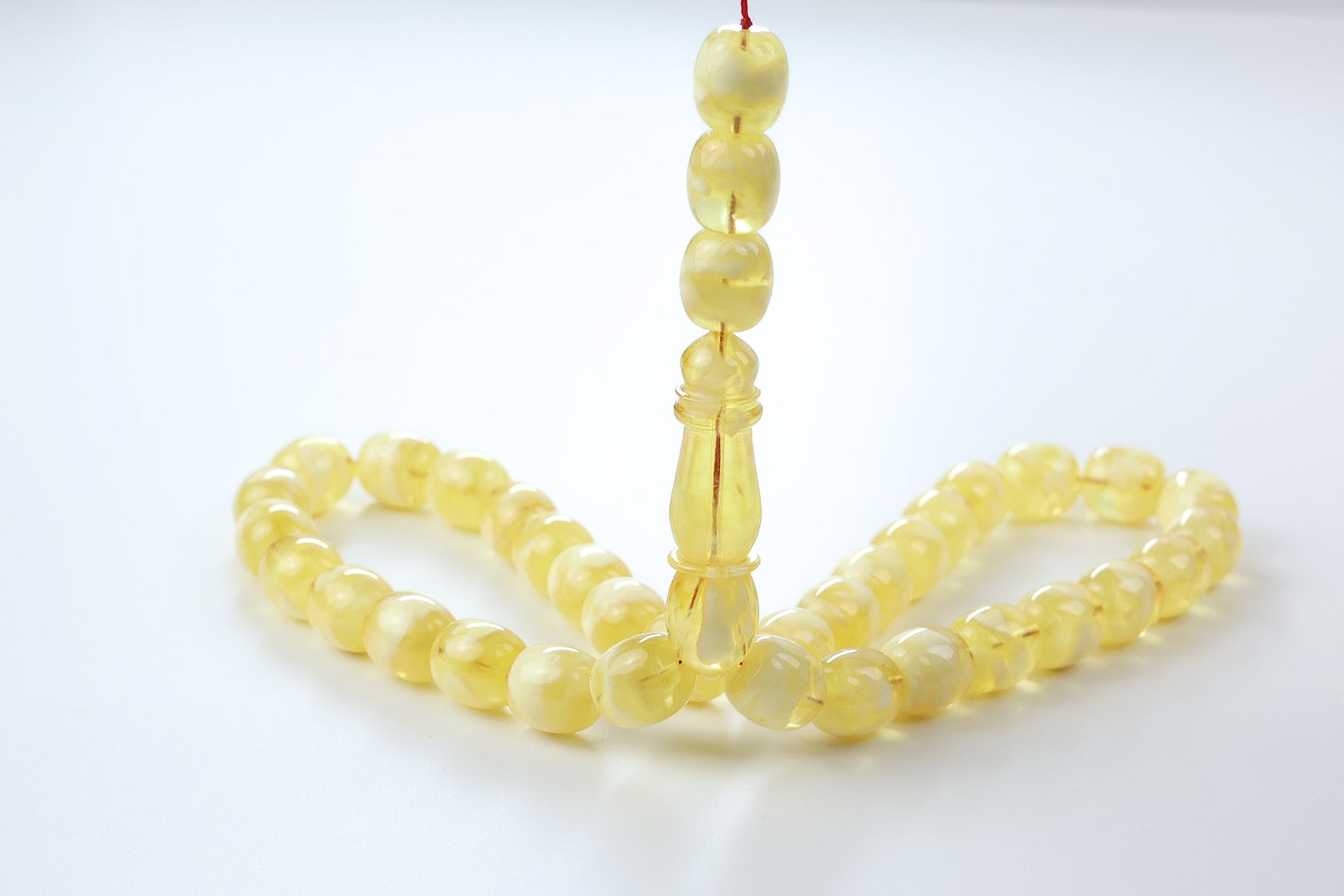 pressed Baltic amber misbaha in light yellow with translucent beads and polished imam centerpiece.
