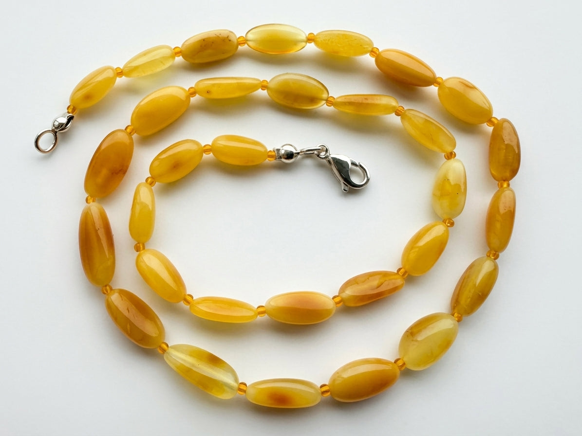 A yellow amber bead necklace with a silver lobster clasp, displayed on a clean white background.