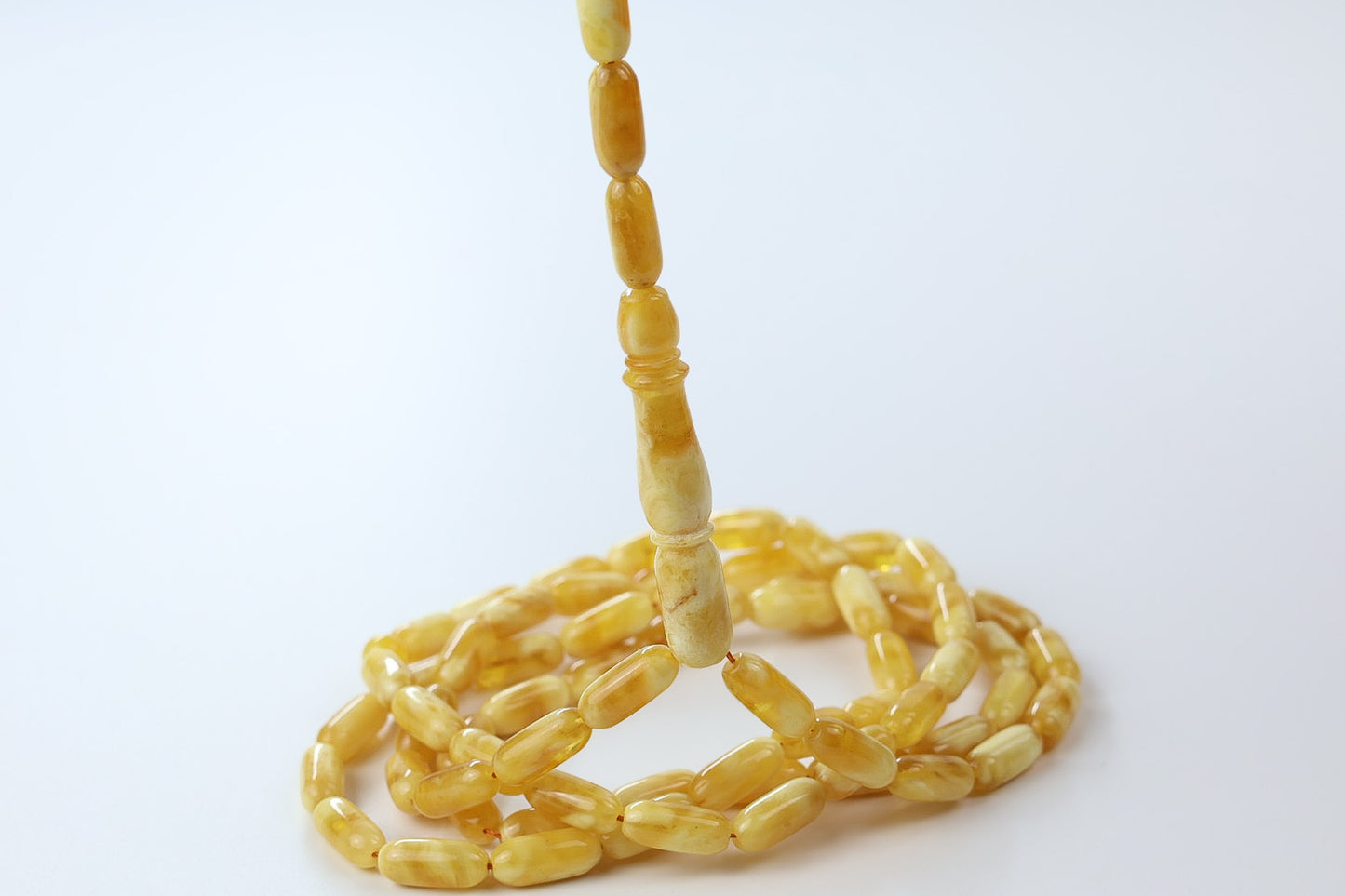 Close-up of Tetibel pressed amber tasbih with glossy yellow oval beads and elongated amber imam detail, premium Islamic prayer beads for Europe.