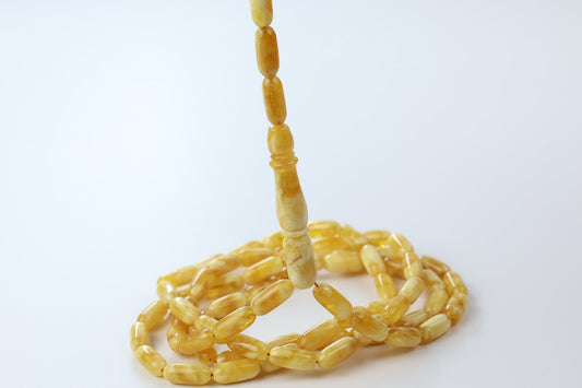 Close-up of Tetibel pressed amber tasbih with glossy yellow oval beads and elongated amber imam detail, premium Islamic prayer beads for Europe.
