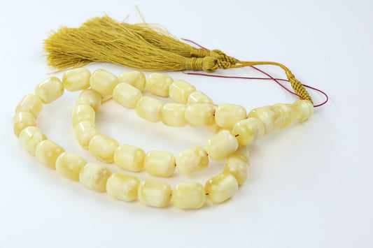 Macro view of milky yellow pressed amber beads with smooth polished finish.