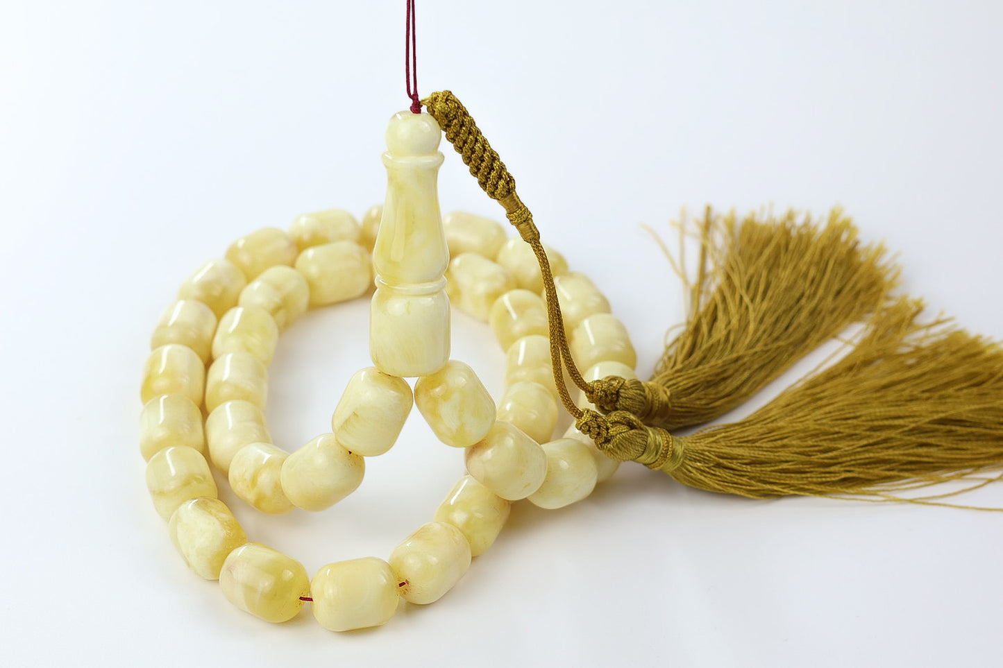 Side angle view of light yellow pressed amber rosary with 36 rounded beads.