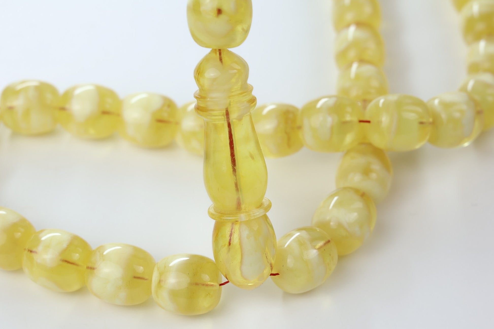 Pressed Baltic amber rosary in light yellow succinite with 33 rounded translucent beads and imam detail, handmade in Poland.