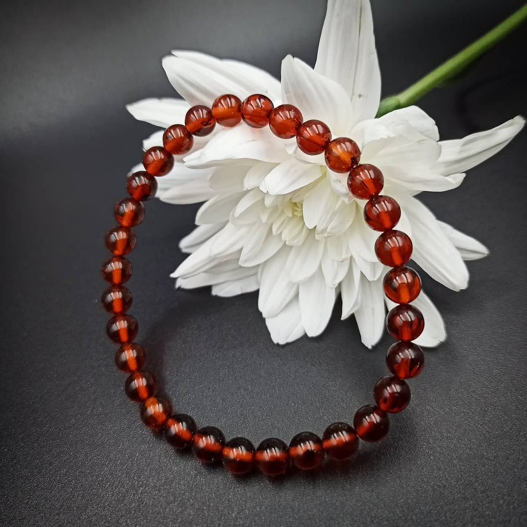 Tetibel deep red genuine amber beaded bracelet on white flower.