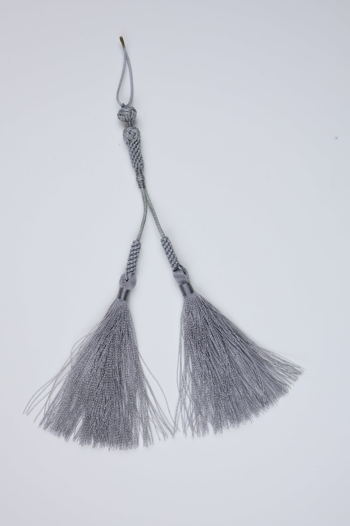 A pair of gray islam tassels with braided cords and metallic silver fringe, displayed on a clean white background.